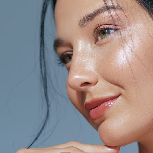 Close-up of a woman's face with Pinkalulu Beauty Lock glow against a light blue background.