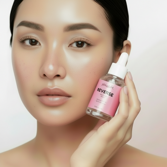 A lady model face holding a bottle of 'Reverse' serum with pink label 