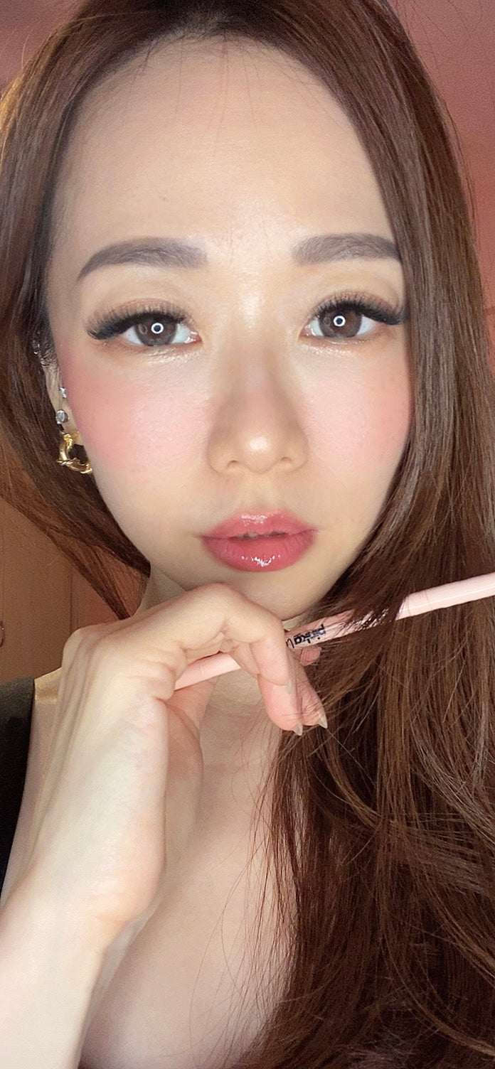 Close-up of a person with long hair holding a makeup product.