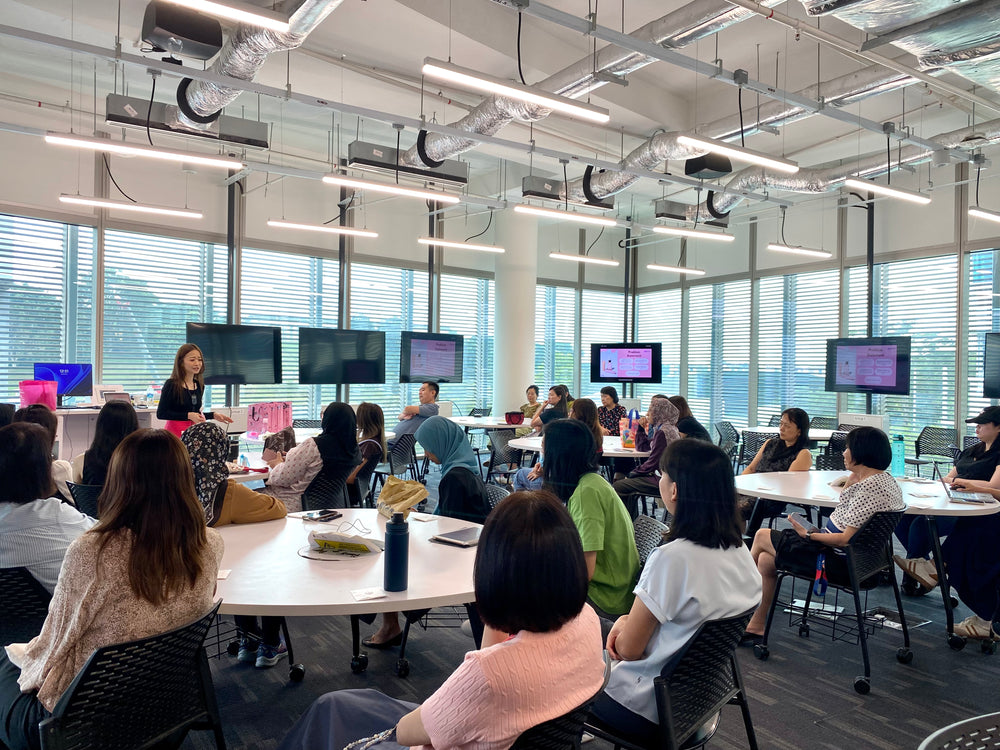 Group of people in a modern office setting with multiple monitors on desks.